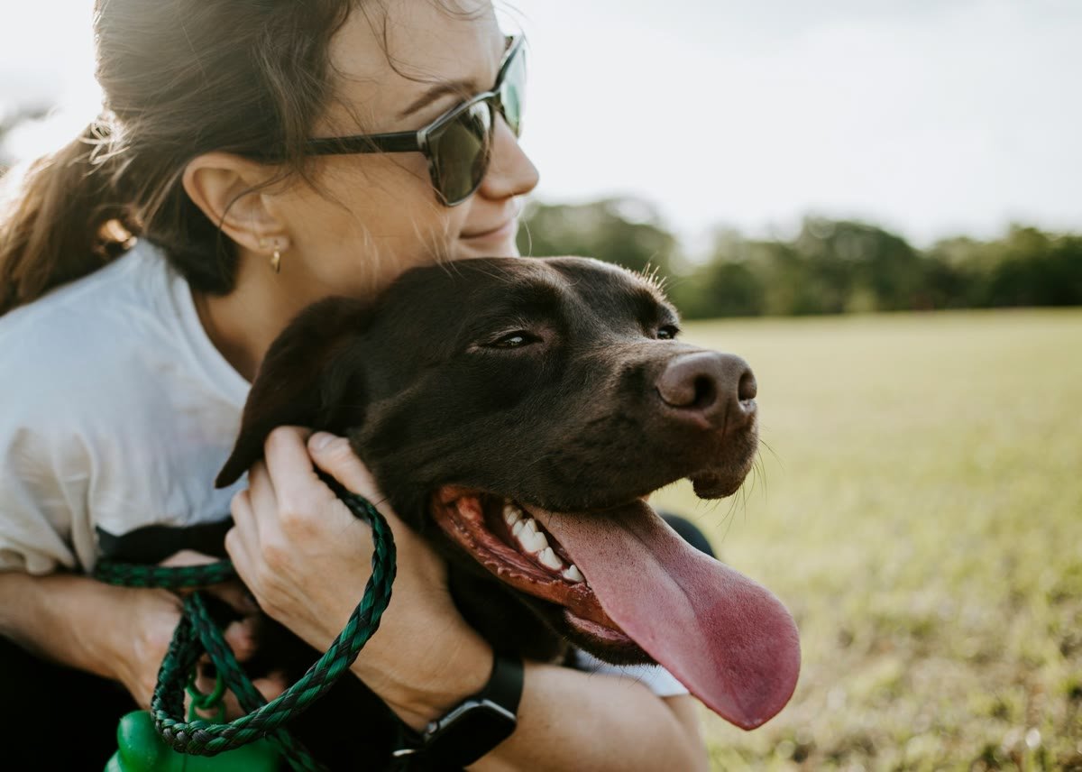 Dueña abrazando cariñosamente a su perro en el campo